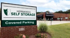 Front entrance sign displaying Hernando Self Storage, Covered Parking with facility in the background